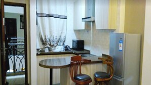 A compact kitchen with a dining area, including a small table and two bar stools.