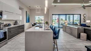 A modern kitchen with a central island, dark cabinetry, and a large window providing a view of the outdoors.