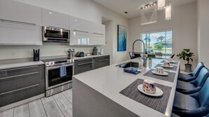 A modern kitchen with stainless steel appliances, a large island with seating, and a view of the outdoors through a window.
