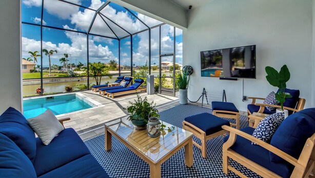A spacious room with a large glass wall overlooking a swimming pool and a clear blue sky.