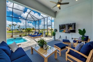 A spacious room with a large glass wall overlooking a swimming pool and a clear blue sky.