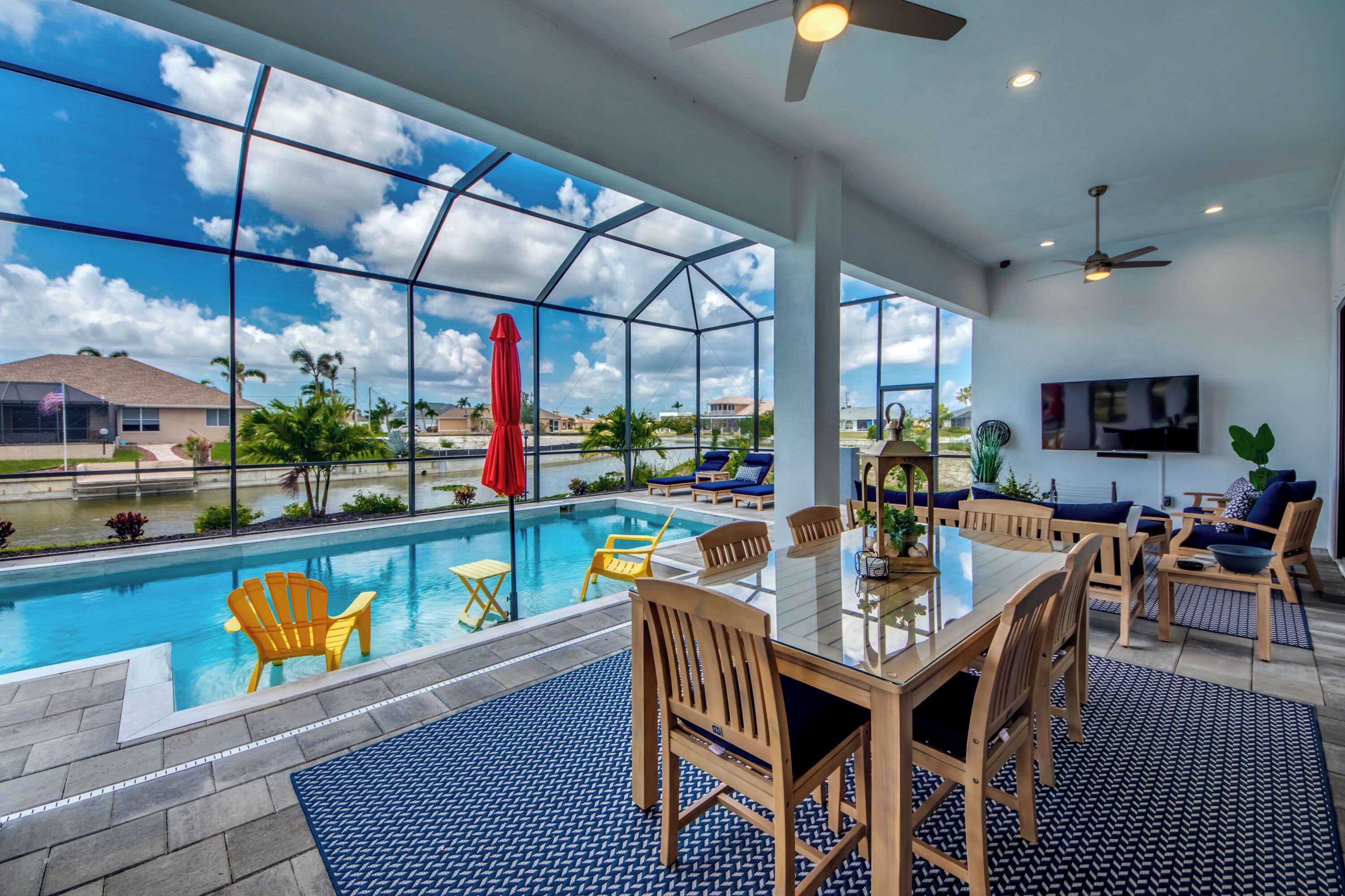 A modern indoor pool area with clear glass walls, wooden furniture, and a view of the surrounding landscape.