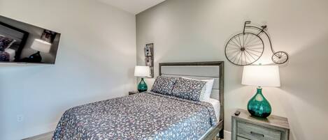 A bedroom with a bed, nightstands, a bicycle wall art, and a ceiling fan.