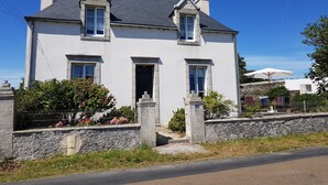 Uma casa de dois andares com telhado cinza, paredes brancas e alicerce de pedra.