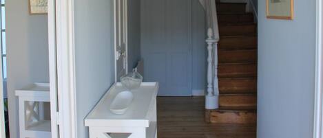 A hallway with a wooden floor, a white bench, and a white sink area.