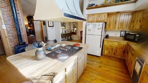 Kitchen area with central island, stove, kettle, and refrigerator.