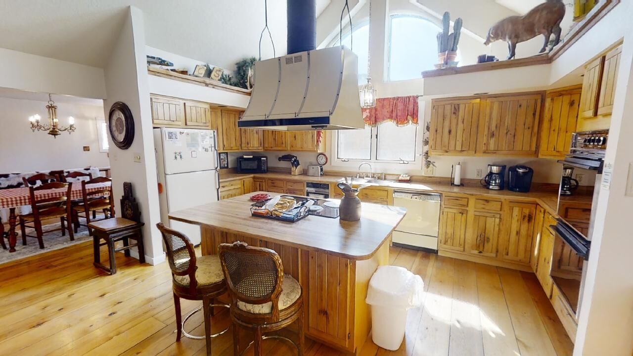 A kitchen with wooden cabinets, a central island, and a dining area with a table and chairs.