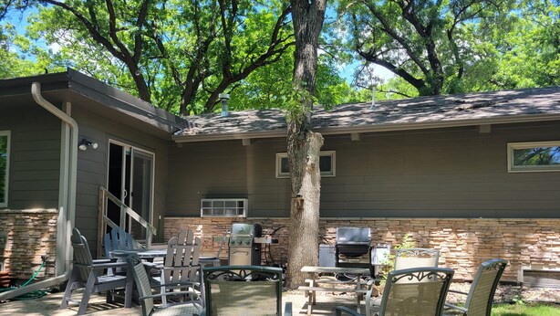 An outdoor patio with a stone fireplace, a grill, and outdoor furniture.
