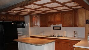 A kitchen with wooden cabinets, a black refrigerator, a white island, and a patterned floor.