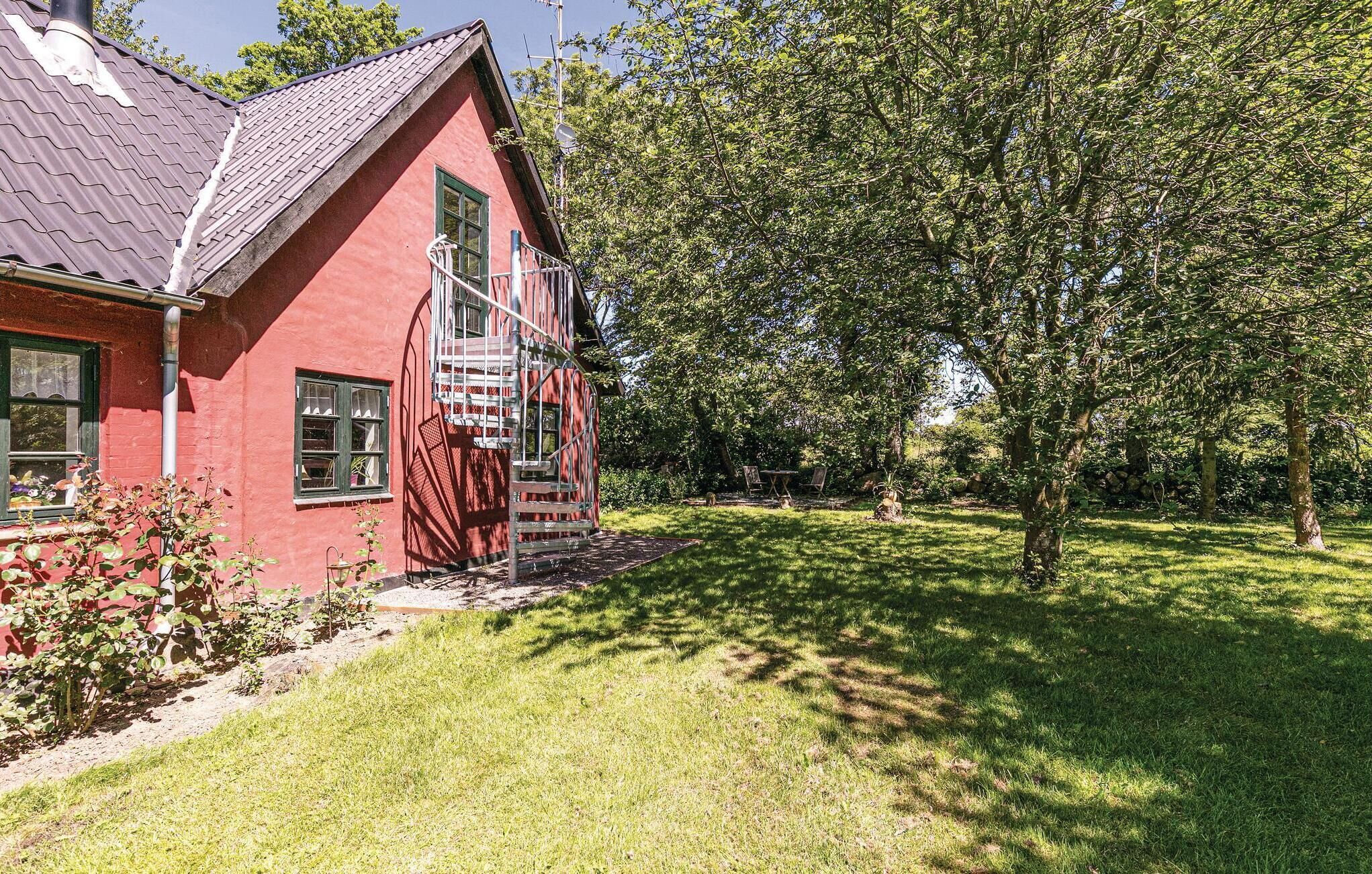 A red building with a metal staircase, surrounded by a grassy area and trees.