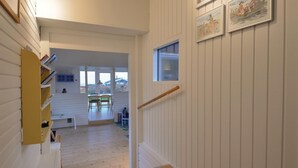 A narrow hallway with white wooden walls, a wooden floor, and a small window. There are two chairs and a table in the background. - Cozy home in Knebel with house sea view (Knebel)