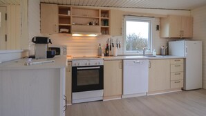 A modern kitchen with wooden cabinets, a Bosch oven, a dishwasher, and a window providing natural light. - Cozy home in Knebel with house sea view (Knebel)