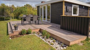 A modern log cabin with a deck, outdoor seating, and a garden area. - Cozy home in Knebel with house sea view (Knebel)