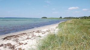 A beach with clear water, sandy shore, and grassy areas. - Cozy home in Knebel with house sea view (Knebel)