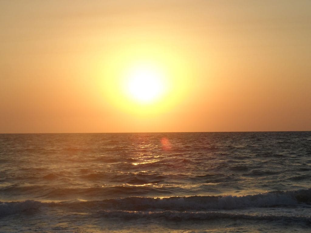 Un coucher de soleil sur l’océan, avec des vagues.