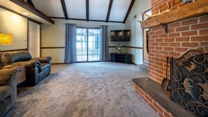 A living room with a fireplace, a sofa, a television, and a large window with curtains. - The Evergreen Home In Lancaster County PA. (Bird in Hand)