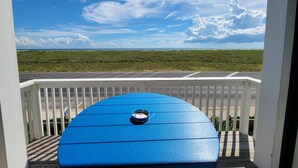 Una tabla de surf azul en un balcón con vista a un estacionamiento y una zona verde.