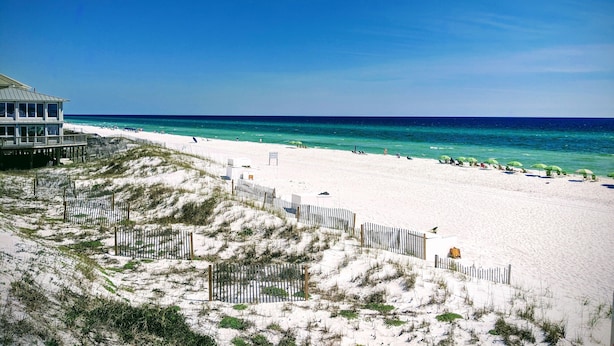 A beach with a wooden fence, a beach house, and the ocean. - Hidden Dunes First Floor Cottage Steps from the Pool, Rare 1 Bedroom, 2 Bathroom (Miramar Beach)