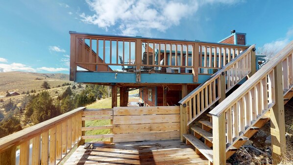 A wooden staircase leading to a deck with a view of a hilly landscape.