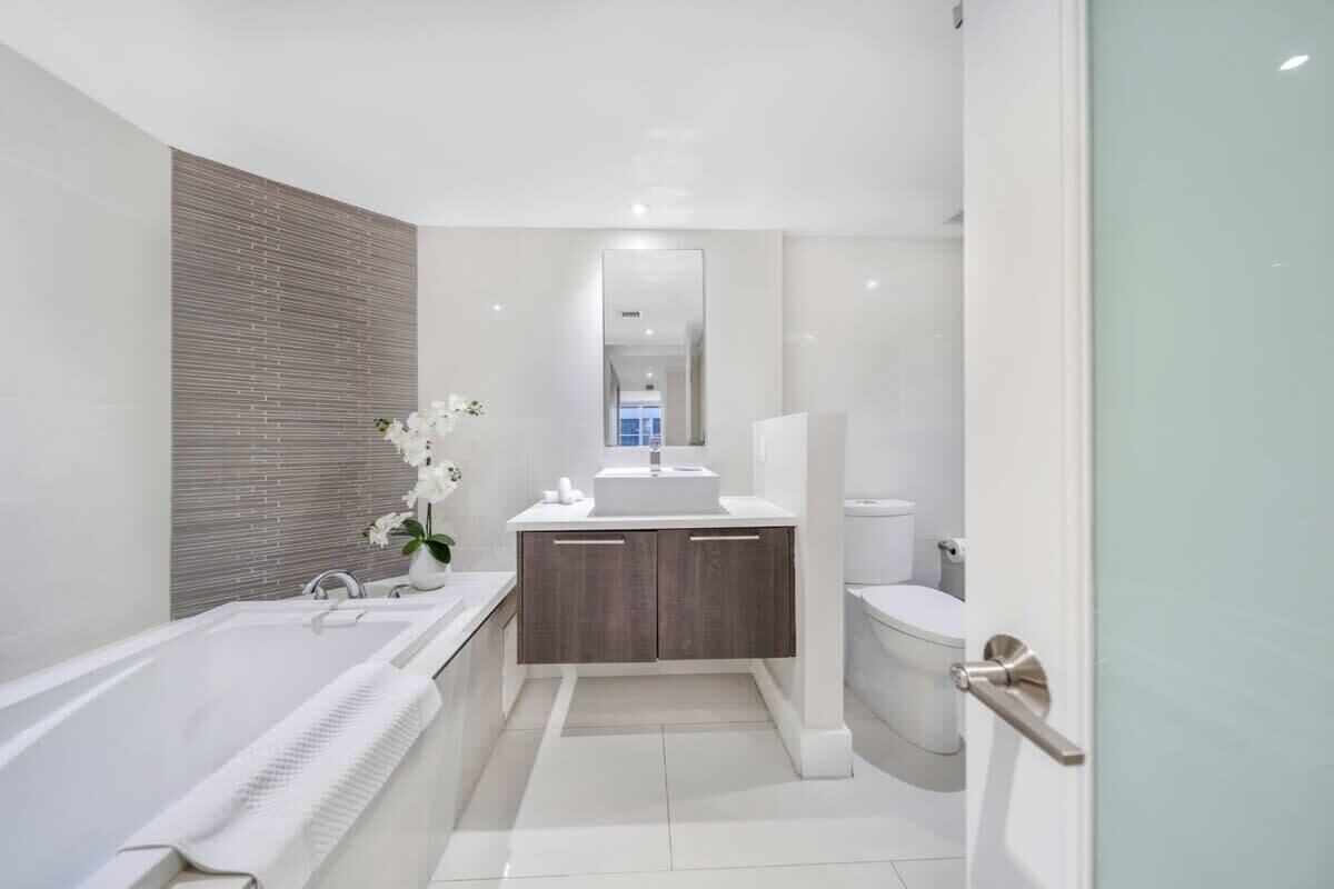 Une salle de bain moderne équipée d’une baignoire, de toilettes et d’un meuble-lavabo avec un miroir.