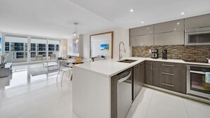 Una cocina moderna con una isla grande, electrodomésticos de acero inoxidable y vistas al exterior.