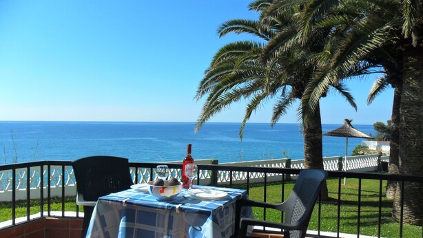 Een terras met een tafel voor twee, met uitzicht op de kust.