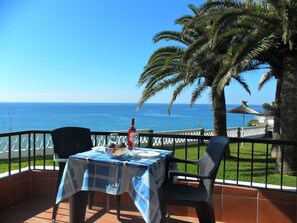 Eine Terrasse mit gedecktem Tisch für zwei Personen, mit Blick auf die Küste.