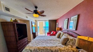 A hotel room with a bed, a wardrobe, a ceiling fan, and a view of the sea.