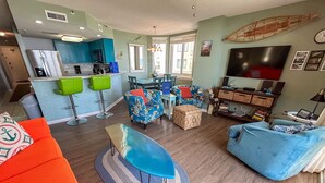 Una sala de estar moderna con un sofá azul, un sofá naranja y una zona de comedor con mesa y sillas.