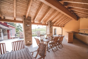 An outdoor patio with wooden furniture and a brick wall. - Agriturismo La Martina (Canelli)