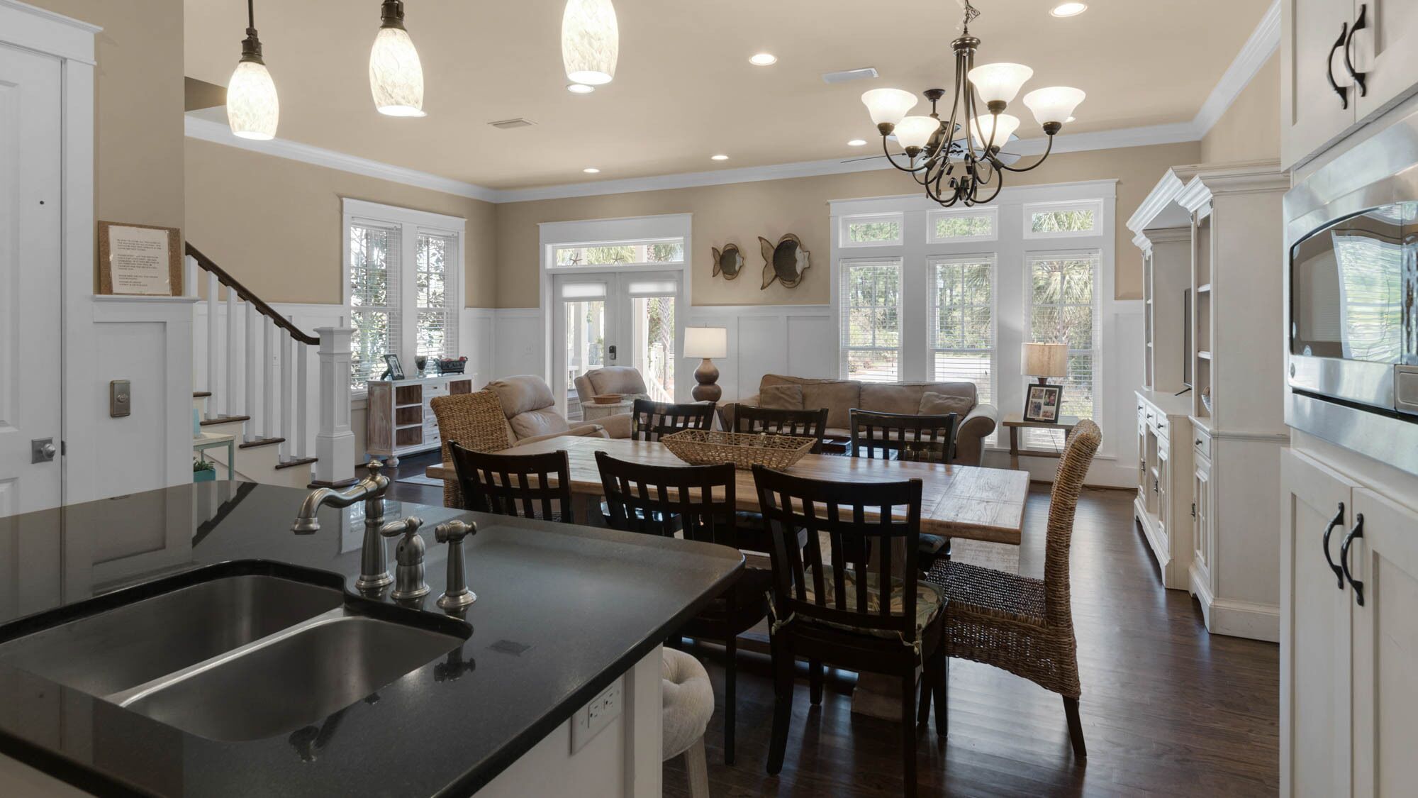 A spacious kitchen with a central island, a dining area with a large table and chairs, and a living room with a sofa and chairs.