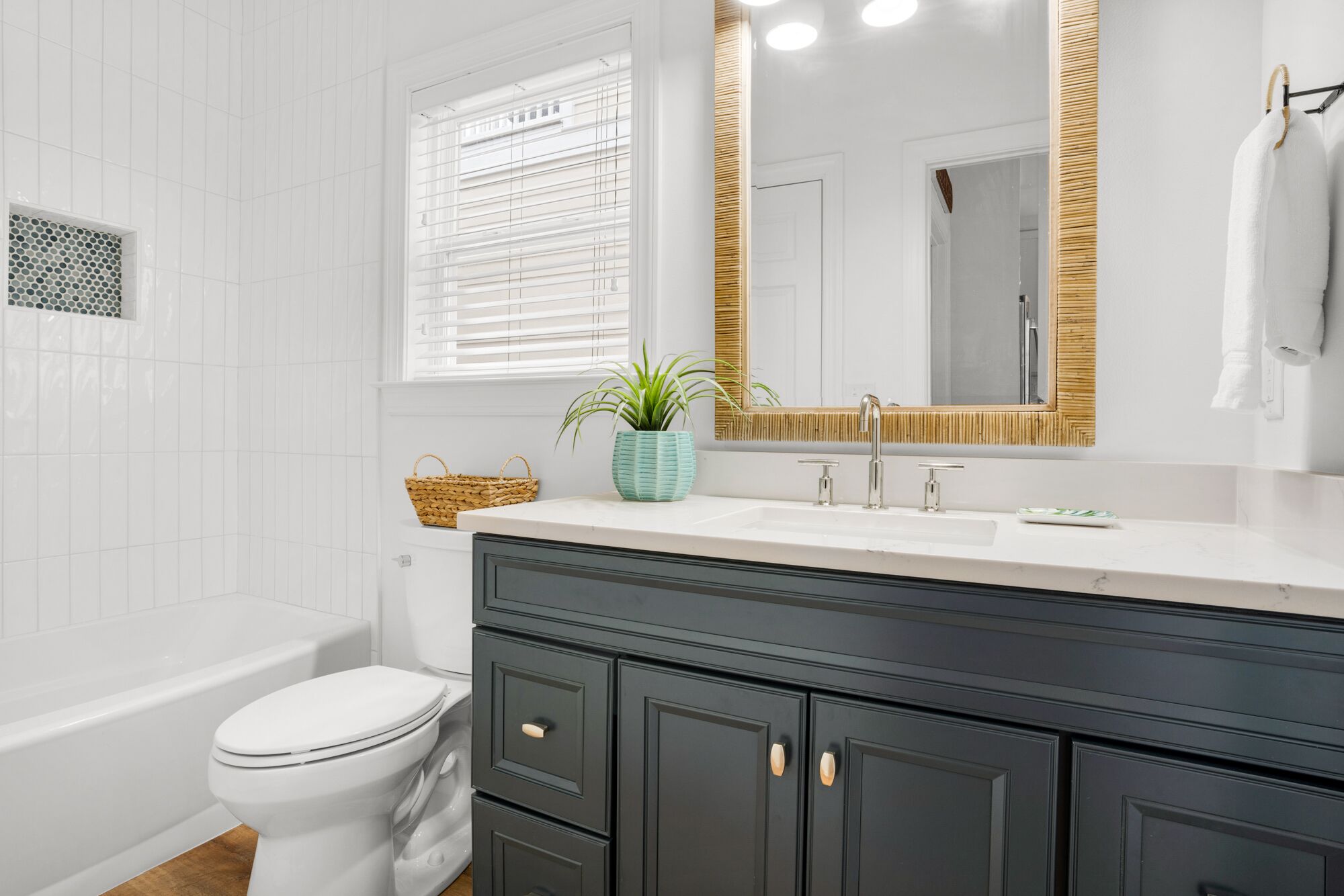 A bathroom with a white toilet, a sink with a mirror, and a vanity with dark cabinets.
