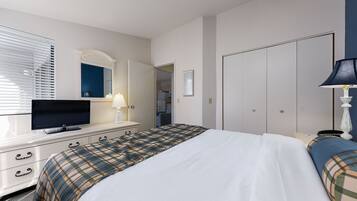 A hotel room with a bed, a TV on a dresser, a lamp, and a wardrobe.