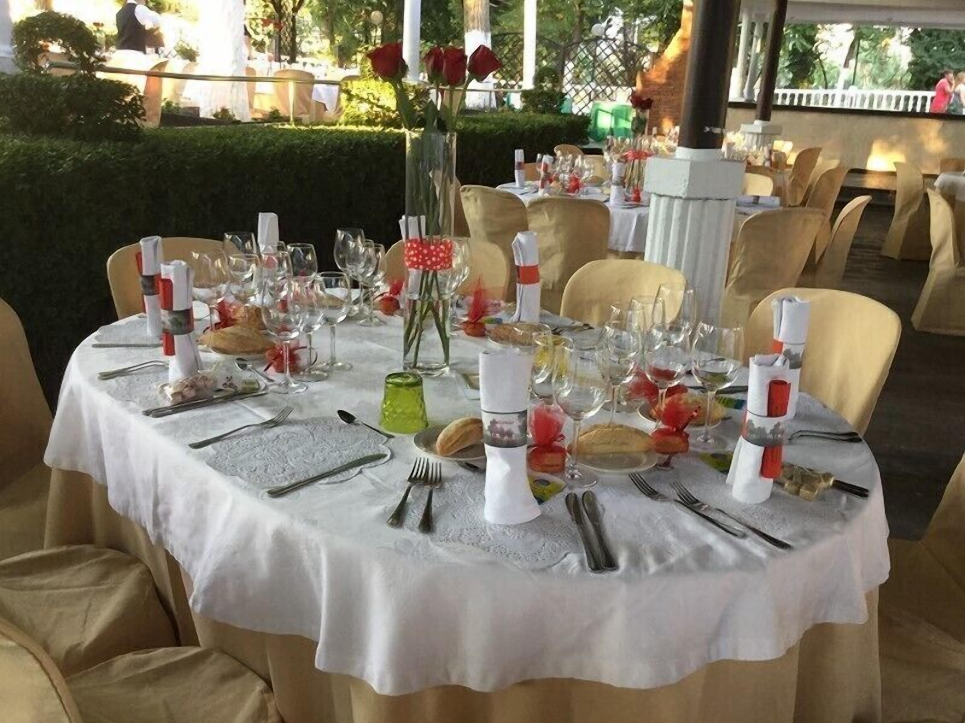 A formal dining table set with white tablecloth, glassware, and red roses.