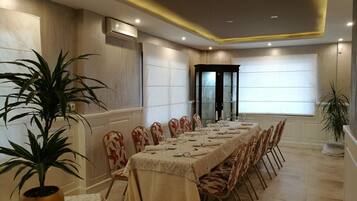 A long dining table set for a meal, surrounded by chairs, in a well-lit room with a modern design.