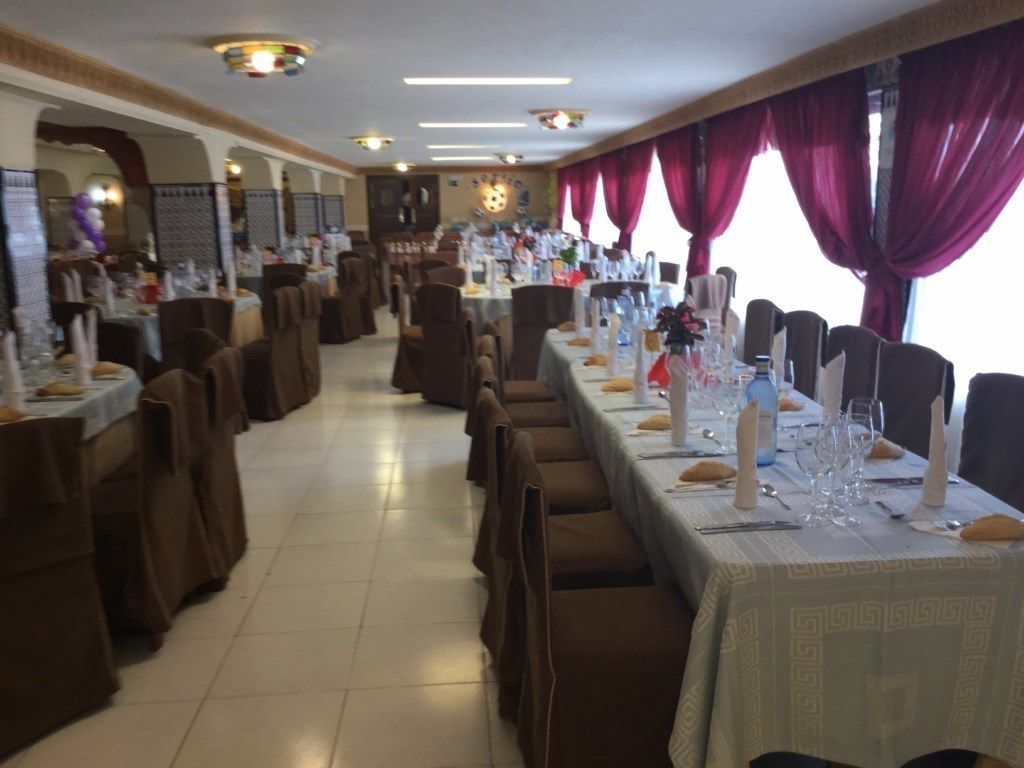 Un restaurante con varias mesas de comedor, cada una con mantel blanco y cubiertos.