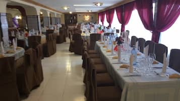 Restaurante com várias mesas de jantar, cada uma posta com toalhas brancas e talheres.