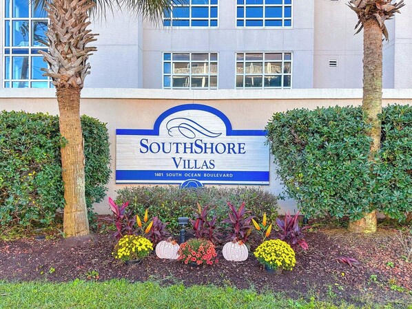 A sign for SouthShore Villas with a clear view of the building's facade and a landscaped garden area.