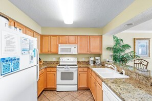 Una cocina con armarios de madera, microondas, estufa, fregadero y refrigerador.