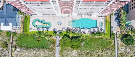 An aerial view of a hotel with multiple swimming pools, a central courtyard, and a modern architectural design.