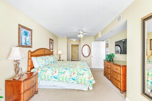 A bedroom with a bed, dresser, mirror, and ceiling fan.