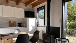 A modern kitchen with white cabinets, a black stove, and a dining area with two chairs.