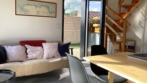 A cozy living area with a sofa, a dining table, and a staircase leading to an upper level.