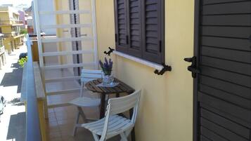 A balcony with a table and chairs, a potted plant, and a door.
