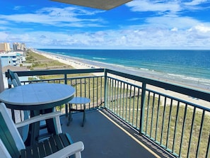 A balcony with a table and chairs overlooking a beach and ocean. - North Shore Villas 801 (North Myrtle Beach)
