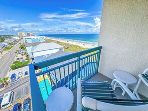 Un balcon avec vue sur la plage et l’océan, une piscine et un espace salon extérieur.