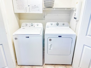 Une buanderie équipée de deux machines à laver à chargement frontal et d’un meuble de rangement au-dessus.