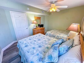 A bedroom with two beds, a ceiling fan, a dresser, and a mirror. - North Shore Villas 801 (North Myrtle Beach)