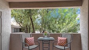 A balcony with two chairs and a table, featuring a view of trees and a building in the background. - Poolside Resort Style Awesomeness (Phoenix)