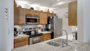 A modern kitchen with wooden cabinets, stainless steel appliances, and a granite countertop. - Poolside Resort Style Awesomeness (Phoenix)